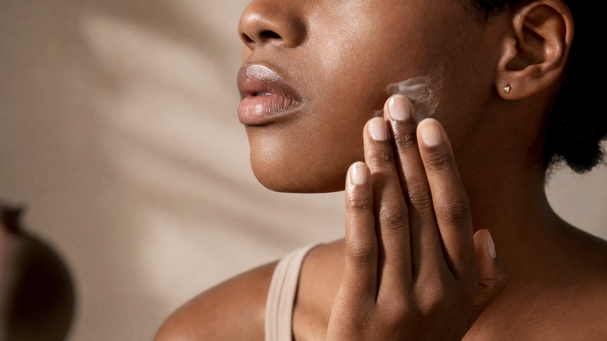 Ozempic face: woman moisturising her jawline as part of skin care during weight loss